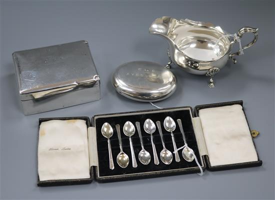 A circular silver tobacco box, a sauce boat, a cigarette box and a cased set of coffee spoons